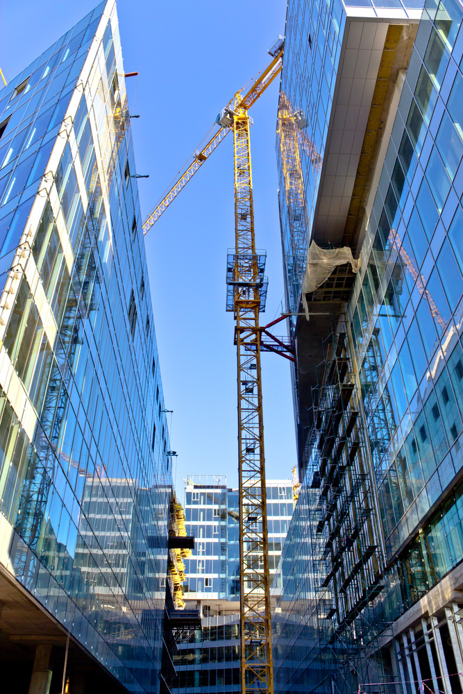 Tall buildings under constructions with tall cranes and scaffolding
